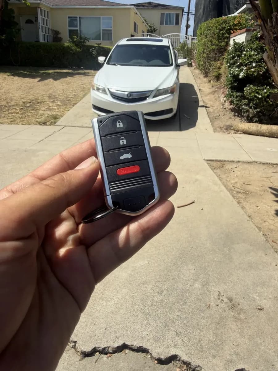 Acura smart key held in front of an Acura ILX outside a Pacific Beach home