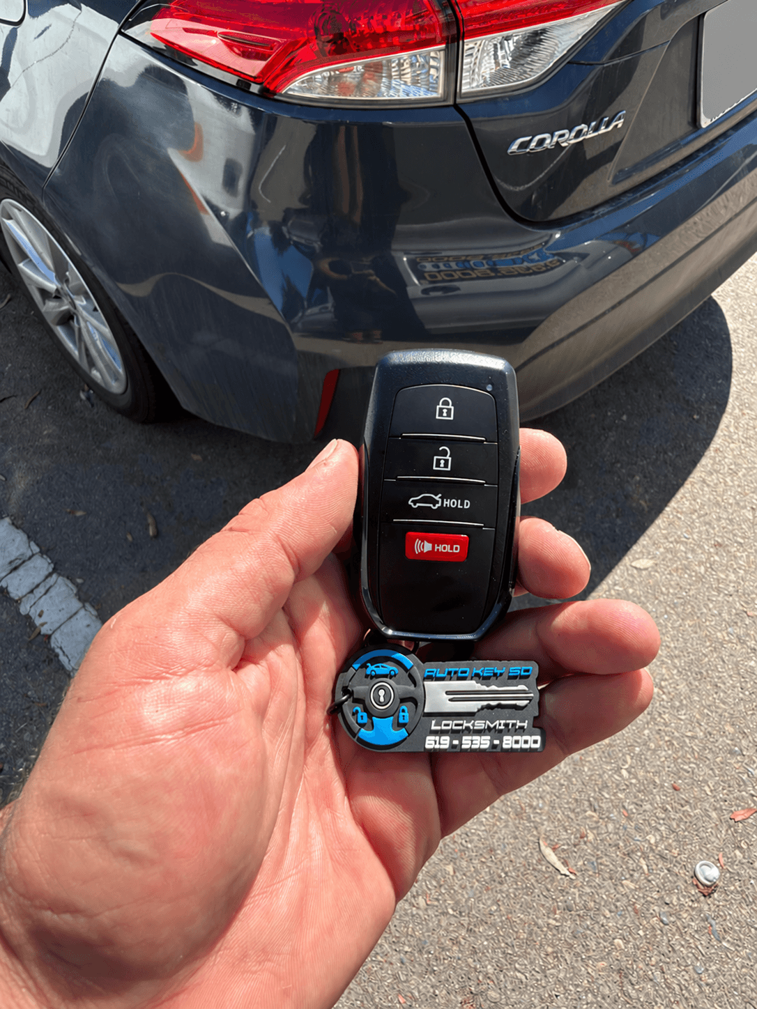 Toyota key fob with an Auto Key SD tag beside a Toyota Corolla; license plate concealed.
