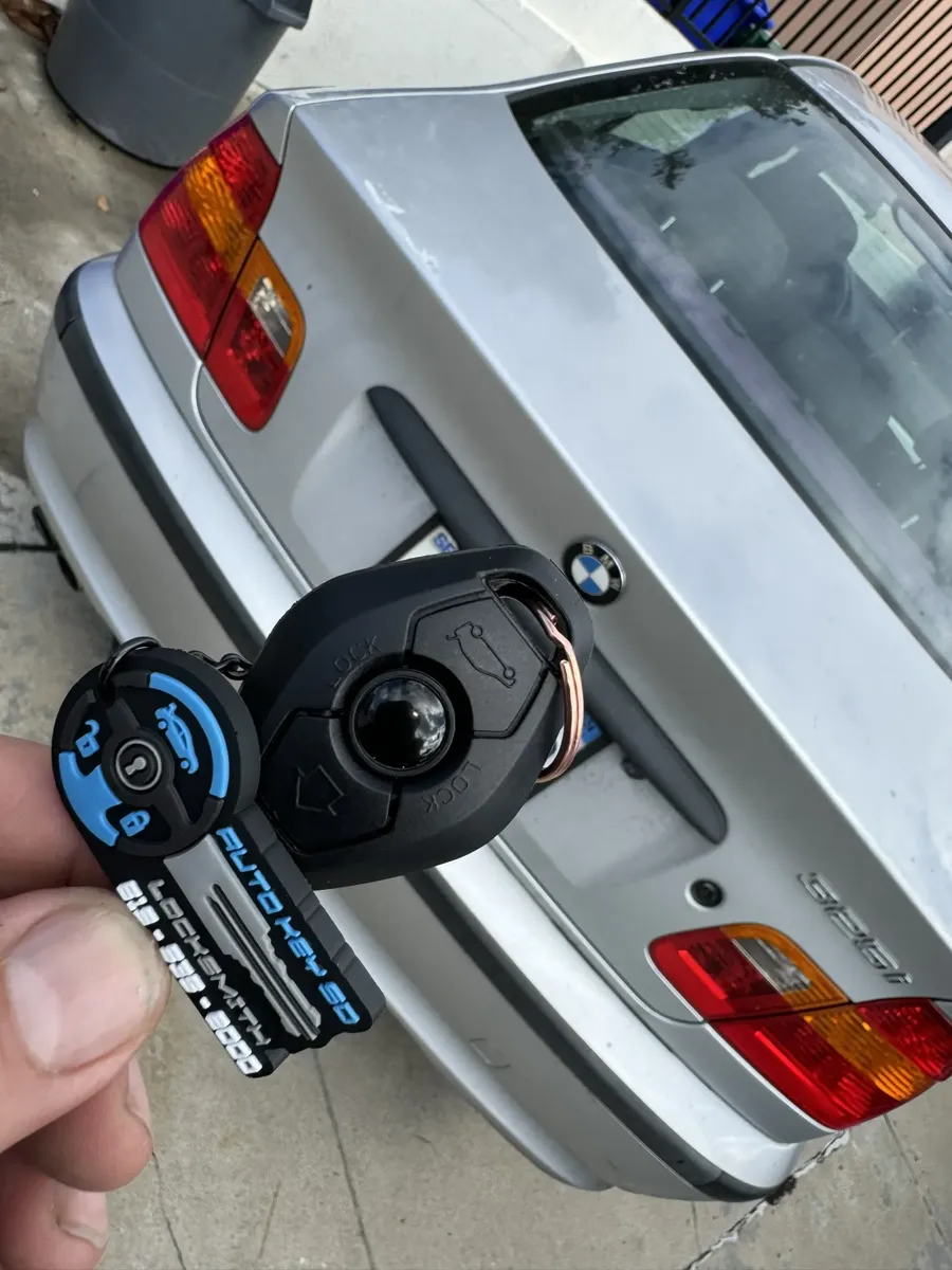 BMW remote key held over the trunk of a silver BMW 325i