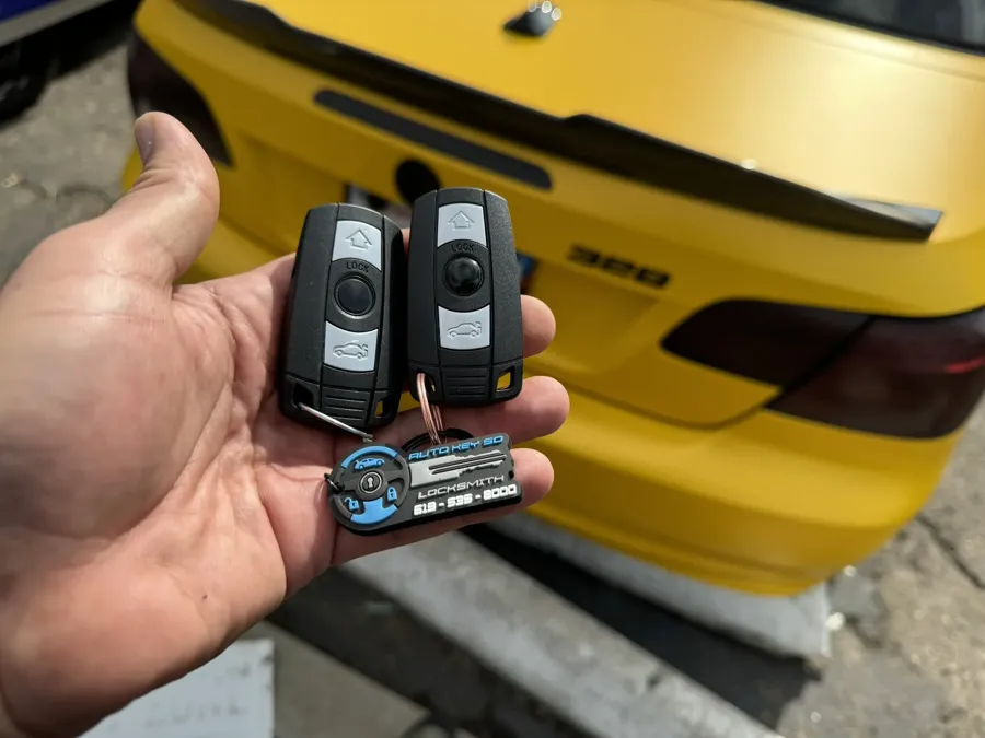 Two BMW smart keys held behind a yellow BMW 3 Series