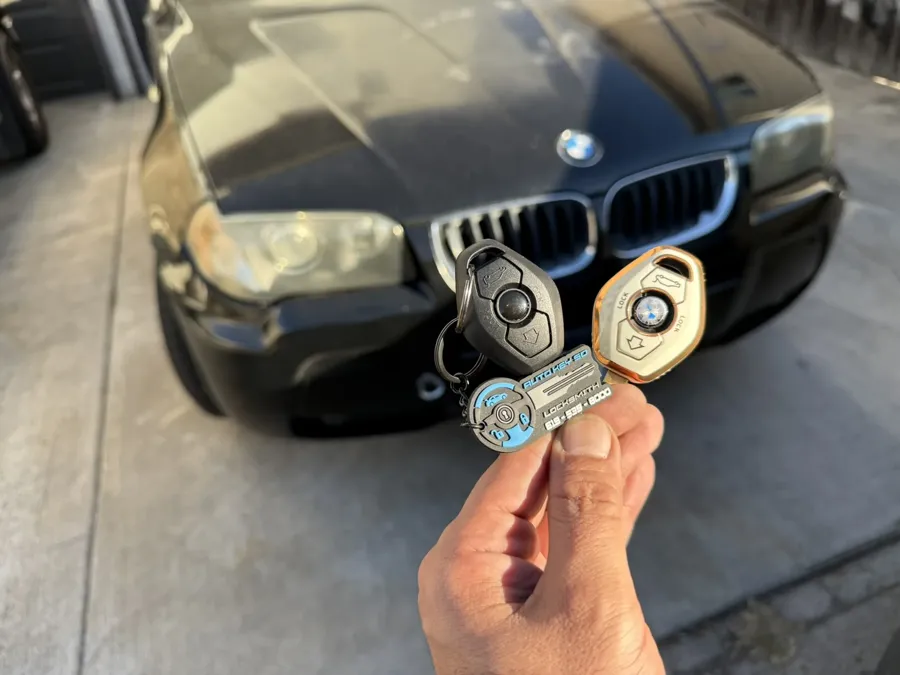 Two diamond-shaped BMW remote keys held in front of a BMW X3