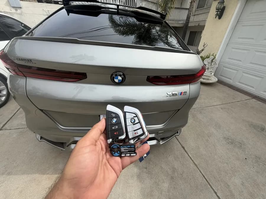 Two BMW smart keys held behind a BMW X6 M