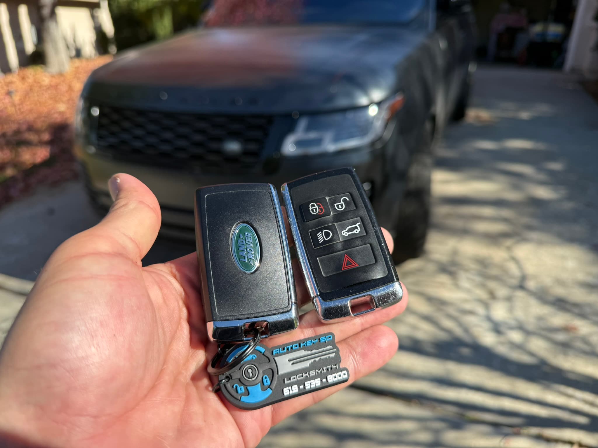 Land Rover key fobs held in front of a vehicle with an Auto Key SD tag